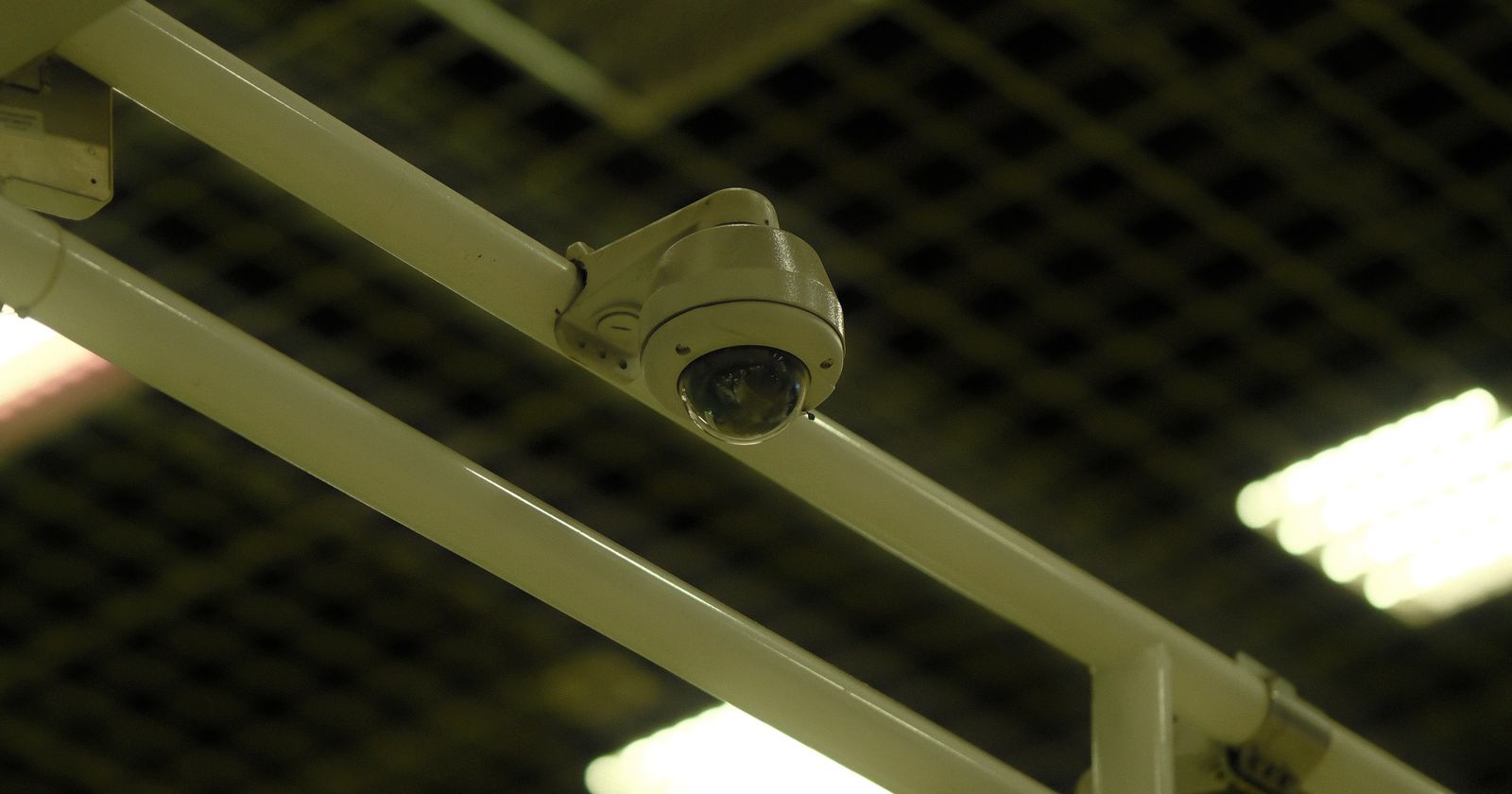 A ceiling-mounted dome security camera on a gantry, looking down over an industrial interior